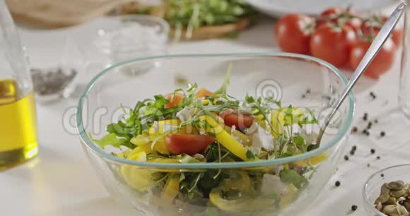 南瓜种子掉进一个玻璃碗里里面放着樱桃番茄黄色的辣椒和绿色的胡瓜洋葱葱视频的预览图