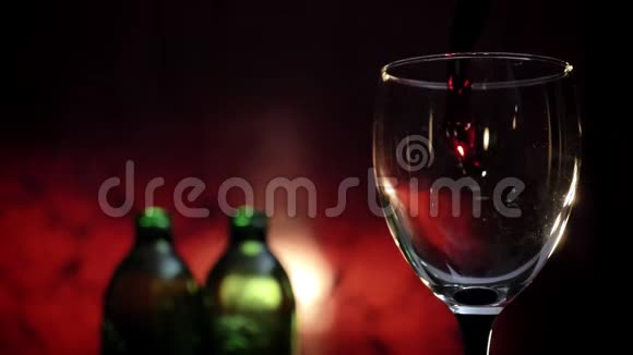 在高脚杯中倒入红酒液体四处飞溅两瓶深红色背景4k视频视频的预览图