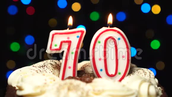 70号在蛋糕上面70号生日蜡烛燃烧在最后吹灭彩色模糊背景视频的预览图