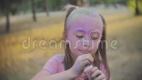 可爱的小女孩在阳光明媚的日子里在公园里吹肥皂泡视频的预览图