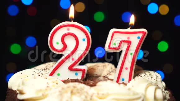 27号在蛋糕上面27号生日蜡烛燃烧在最后吹灭彩色模糊背景视频的预览图