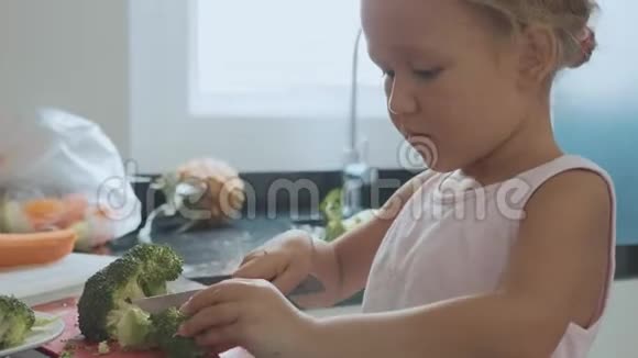 一个小女孩在家里的厨房里切布罗利做菜视频的预览图