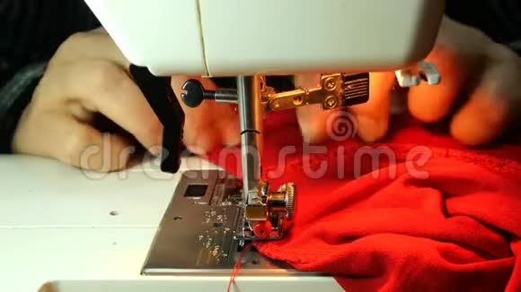 裁缝工作的过程老年女裁缝用针缝红布的衣服视频的预览图