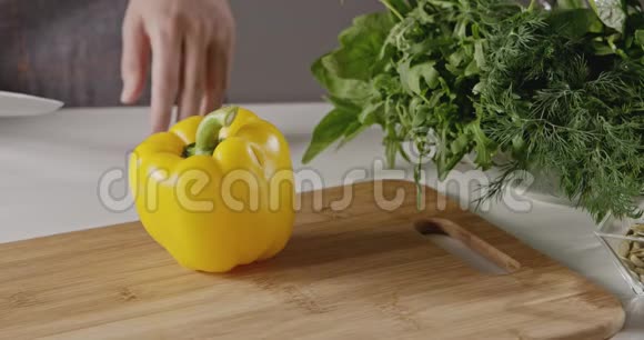 穿着围裙的女人用刀子在切割的木板上砍下一个黄色的胡椒纸慢动作全高清视频视频的预览图