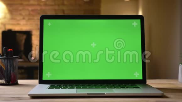笔记本电脑的特写镜头办公桌上有绿色屏幕室内有商人在模糊视频的预览图