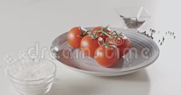 4K全景慢镜头白色餐桌上蓝色陶瓷盘上的樱桃西红柿特写胡椒视频的预览图