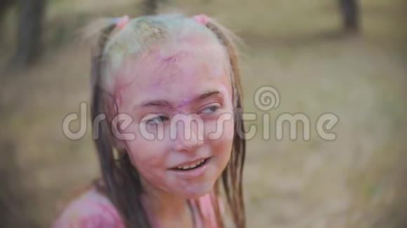 小女孩涂上了霍利的颜色笑着享受着水溅在脸上的乐趣视频的预览图