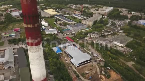 绿林环绕的工业区机库和其他厂房上方的红白相间烟囱视频的预览图