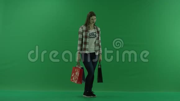 带着购物袋的女孩站在半个转弯处站在她的右边在绿色的屏幕上微笑视频的预览图