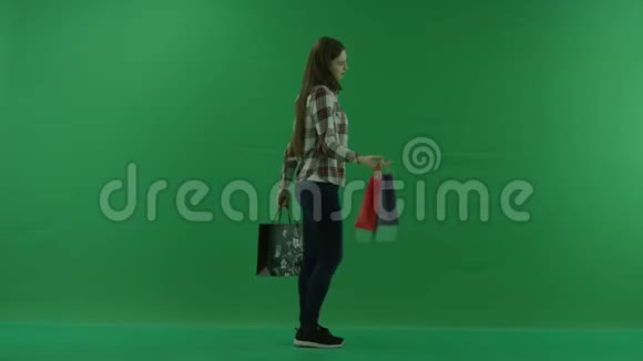 手里拿着袋子的女孩站在她的右边在绿色的屏幕上跳舞视频的预览图