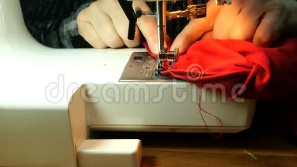 裁缝工作的过程老年女裁缝用针缝红布的衣服视频的预览图