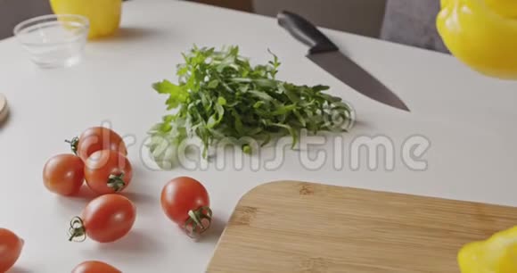 穿围裙的女人在切割木板上放了一个黄色的胡椒纸背景与烹饪沙拉的原料视频的预览图