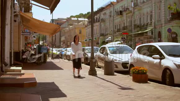 一位妇女沿着美丽的街道散步的正面景色视频的预览图