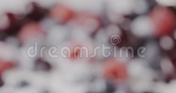 一个成熟多汁樱桃覆盆子蓝莓与牛奶酸奶的特写改变浆果背景的焦点慢慢视频的预览图