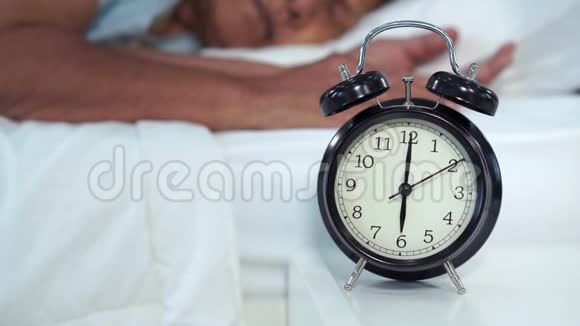 睡在床上的老妇人在早晨闹钟上按小睡按钮视频的预览图