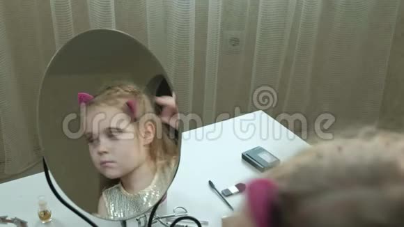 一个红头发的小女孩把发夹固定在头发上试穿配饰照镜子化妆洗脸时尚视频的预览图