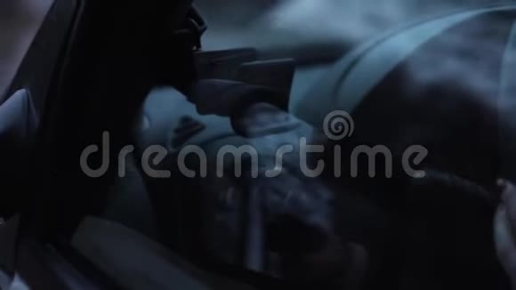 一个年轻的女人晚上坐在汽车的车轮前视频的预览图