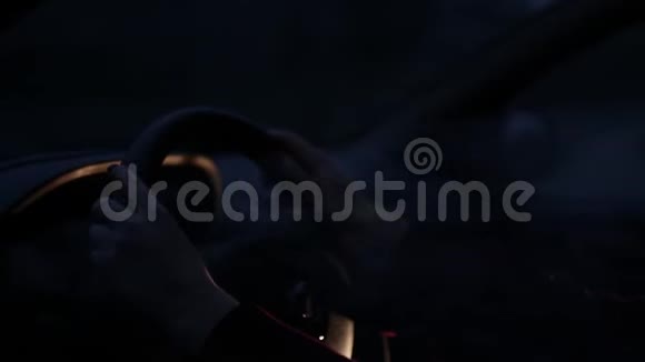 一个年轻的女人晚上坐在汽车的方向盘上视频的预览图