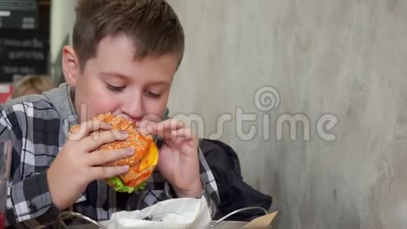 一个在咖啡馆里吃汉堡包的少年他又饿又好吃又多汁的汉堡视频的预览图