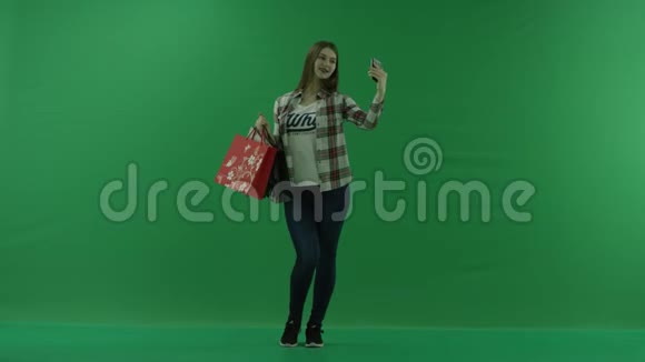 女孩带着购物袋站在半个转弯处向右看在绿色屏幕上自拍视频的预览图