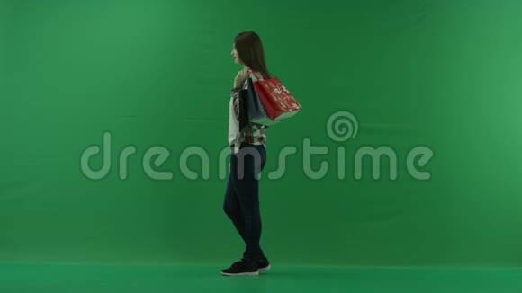 女孩肩上拿着购物袋站在左边在绿色的屏幕上微笑视频的预览图
