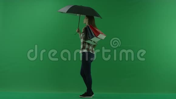 肩上扛着包的女孩站在绿色屏幕上的雨伞下视频的预览图