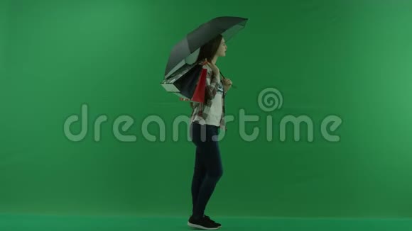 肩上挎着包的女孩站在绿色屏幕上的雨伞下视频的预览图