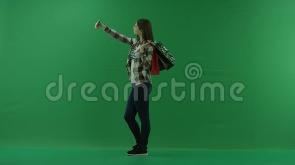 女孩肩上扛着购物袋站在左边在绿色屏幕上自拍视频的预览图