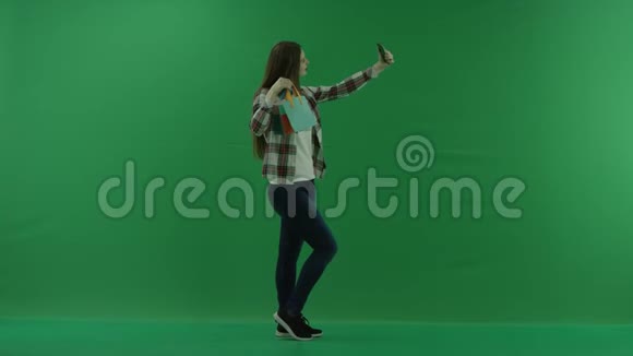 带迷你包的女孩站在她的右边在绿色屏幕上自拍视频的预览图