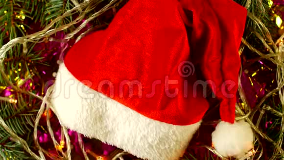 木制背景和红色圣诞帽上的圣诞灯和云杉枝2019年新年圣诞节圣诞节视频的预览图