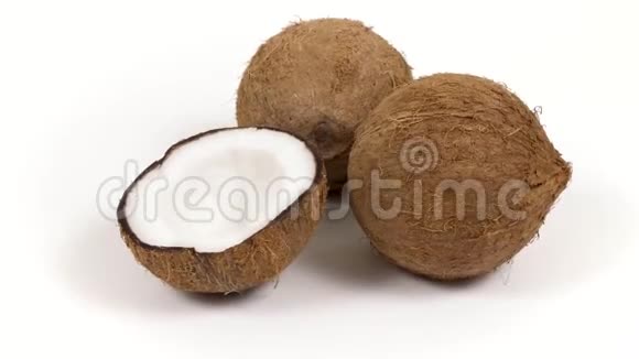 两个完整的椰子和一半的美味果肉旋转在白色的孤立背景可循环无缝视频的预览图