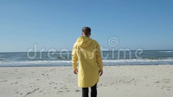 穿着雨衣的沙滩上的男人慢慢地举起双手视频的预览图