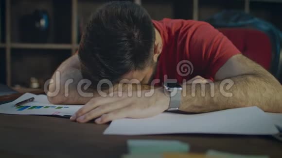 疲惫的商人躺在桌子上的文件上商人睡在桌子上视频的预览图