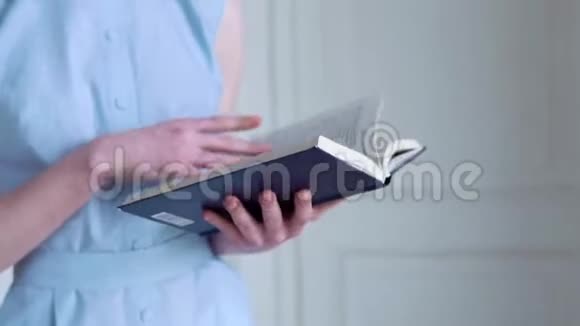 年轻的红头发女孩拿着一本书在白屋子里看书视频的预览图