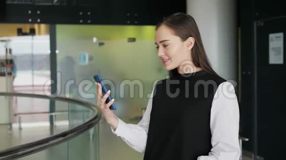 在机场候机楼等待航班时一位开朗的女商人在智能手机上发短信快乐的微笑女孩模特视频的预览图