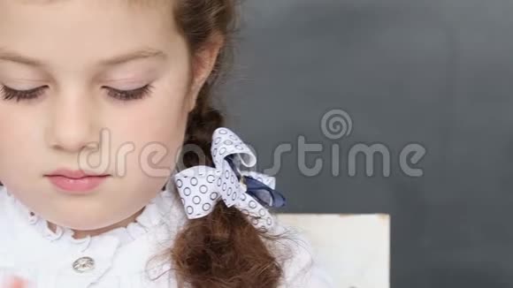 小女孩坐在学校的办公桌前视频的预览图