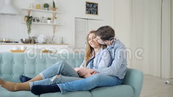 男人拥抱坐在沙发上的女士在厨房里接吻视频的预览图