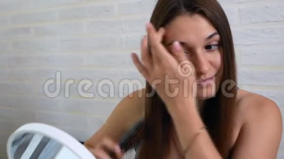 年轻漂亮的女人在镜子前梳头视频的预览图