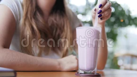 年轻漂亮的欧洲女孩在炎热的夏日在咖啡馆里喝着冰镇牛奶鸡尾酒和蓝莓妇女饮酒视频的预览图