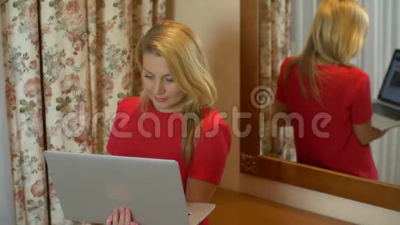 使用笔记本电脑的成年妇女站在镜子后面视频的预览图