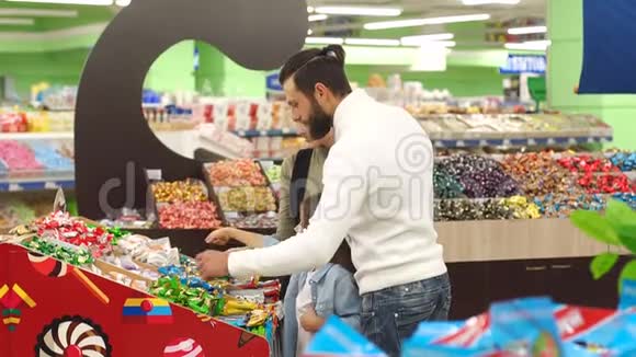 幸福的家庭和一个孩子在超市买糖果和糖果视频的预览图