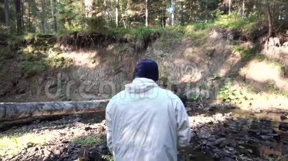 一个人走在森林里在峡谷旁的小径上录像从峡谷和小河的背面看人视频的预览图