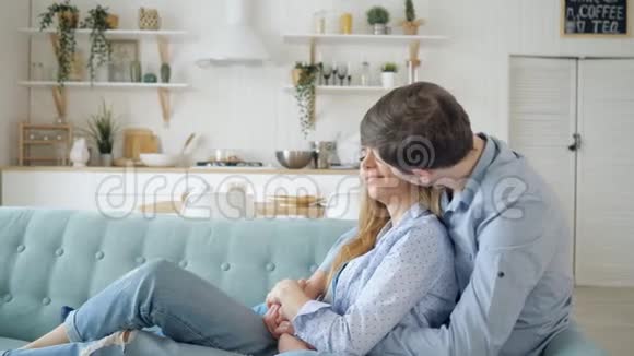 男人拥抱坐在沙发上的女士在厨房里接吻视频的预览图