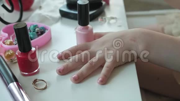 小女孩她的头发是红色的指甲上涂了粉红色的清漆照镜子化妆脸时尚风格化妆品视频的预览图
