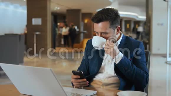 在舒适的大堂酒店商务人员一边喝咖啡一边工作一边使用笔记本电脑视频的预览图