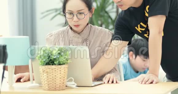 幸福的家庭在家里使用笔记本电脑在线购物和年轻的亚洲儿童玩平板电脑的背景视频的预览图