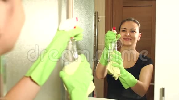 女人在浴室用喷雾瓶清洗镜子视频的预览图