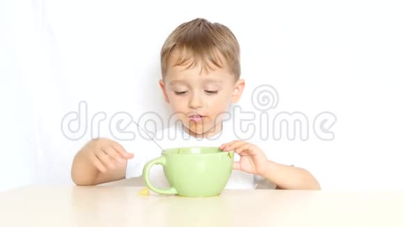 坐在桌旁的小男孩吃完食物把盘子推开视频的预览图