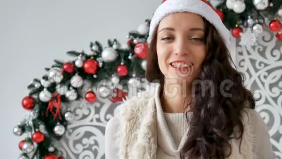 节日和人的概念美丽的女人戴着圣诞帽和卷发在背景下微笑视频的预览图