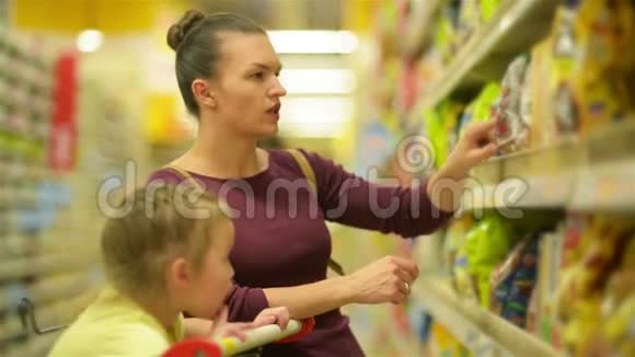 母亲和女儿在超市购物他们正在买早餐片一个女儿坐在超市视频的预览图